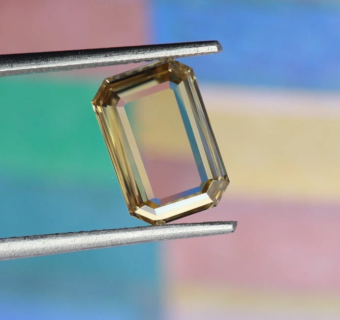 A clean octagon-cut gemstone held in tweezers